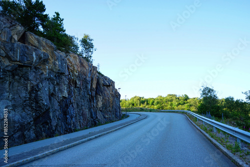 Curved road along rocky hillside in forest landscape