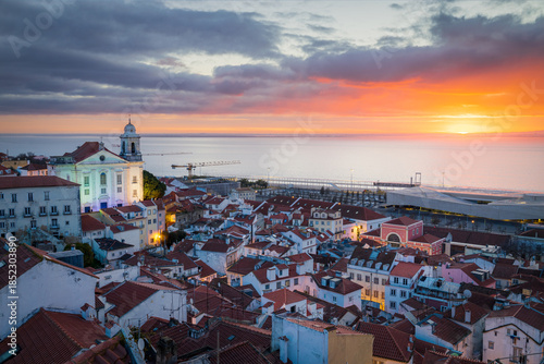 Panoramic view of the Alfama district and Tagus river in Lisbon, from Portas do sol viewpoint, with red rooftops at sunrise