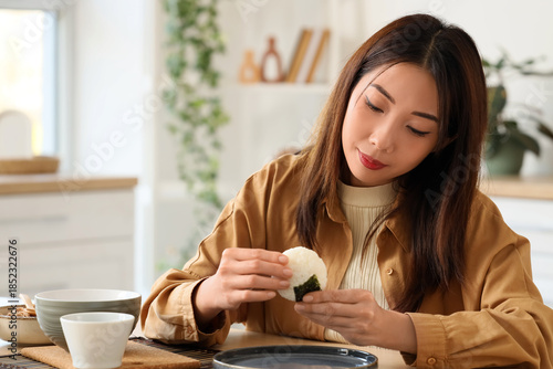 Young woman eating onigiri ...