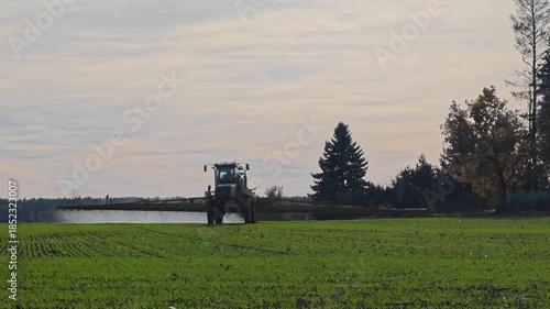 Tractor in the field.Agricultural work.The tractor sprays green shoots in the field.A tractor-mounted irrigation system in operation. 4k footage