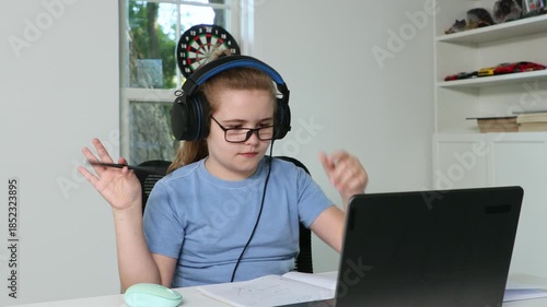 Kid studying at desk. Boy doing home education. Child concentrating on study. Laptop study session for kid. Kid studying at home. Kid taking online class. Child writing in notebook.