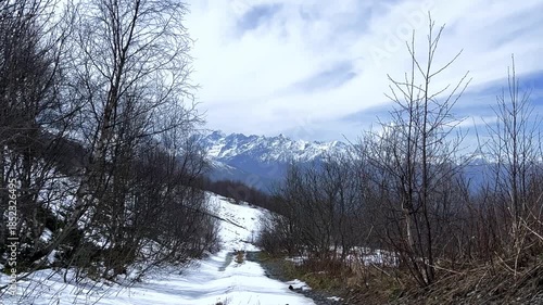 Archonsky Pass. The pass connects the Kurtatinsky gorge with the Alagirsky. Alanya, view of the mountains of the North Caucasus, peaks covered with snow. Sunny day, blue sky with a slight haze. 4К