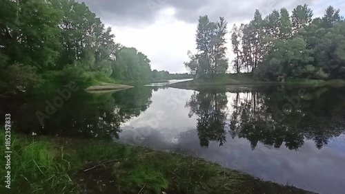 Two banks of a beautiful lake converge leaving a passage for water on a cloudy summer day.