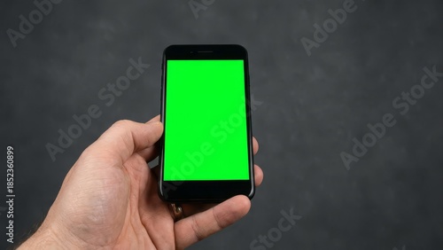 Hand holding smartphone with green screen background