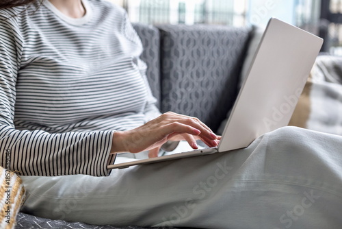 Close-up of woman typing on a laptop while working from home, remote work, digital tasks, productivity and modern lifestyle in a relaxed and cozy interior environment with natural daylight.