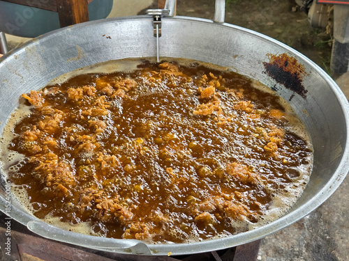 Overhead view of crispy chicken pieces frying vigorously in oil inside a large wok