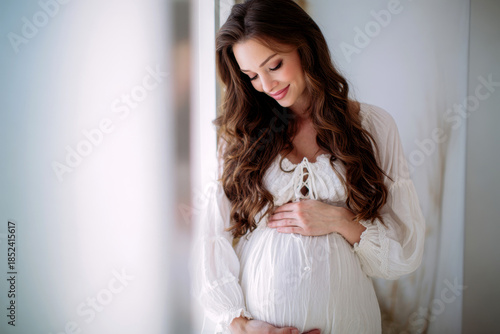 Beautiful pregnant woman touching her belly standing at home.