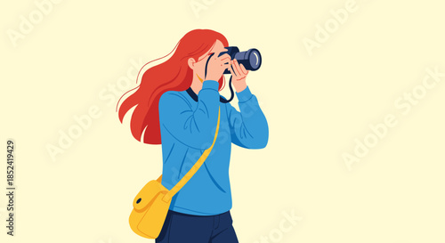 A young female photographer with long red hair focuses and takes a picture with her professional dslr camera on a soft background.