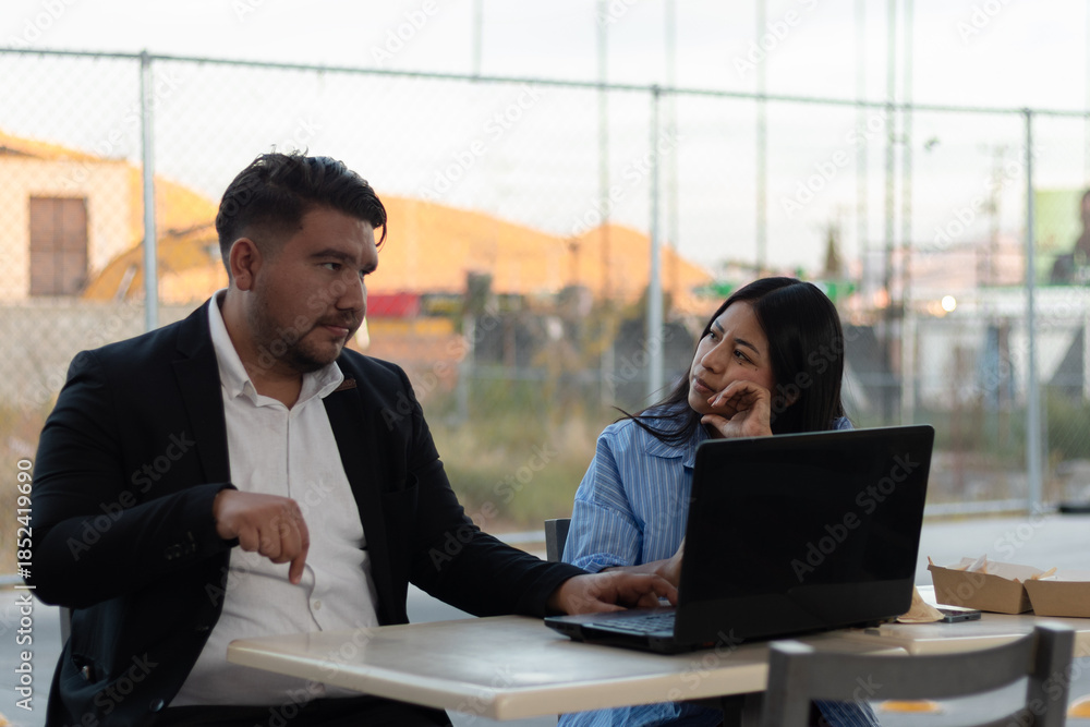 © Rangel - Colleagues collaborating on laptop, experiencing disagreement and boredom during an outdoor business meeting, discussing a project with contrasting engagement