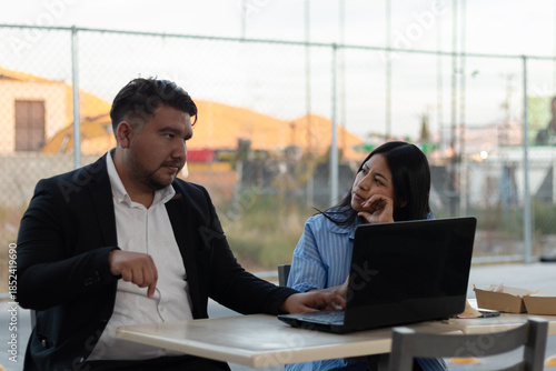 Colleagues collaborating on laptop, experiencing disagreement and boredom during an outdoor business meeting, discussing a project with contrasting engagement