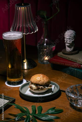 Burger and craft beer in a dimly lit bar setting.
