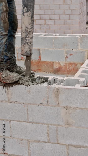 Construction worker skillfully fills concrete into blocks while building structure on works day outdoors.