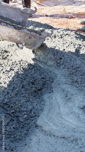 Construction workers skillfully pour wet concrete into foundation form while to foundation slab
