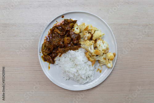 A plate of beef rendang and cauliflower with white rice.