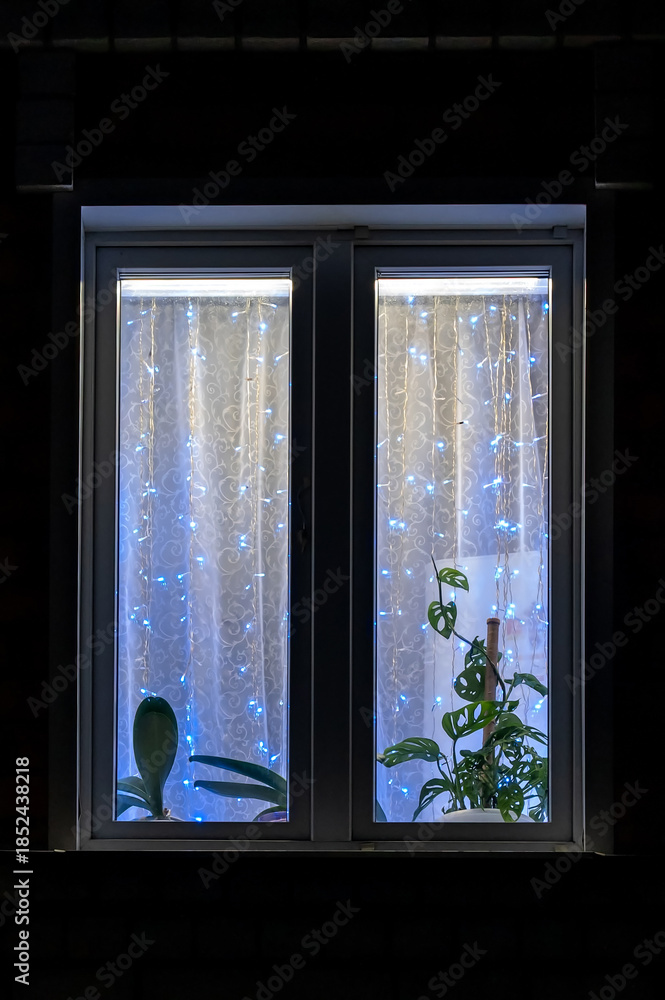 Fototapeta premium Illuminated window of the facade of an apartment building at night.