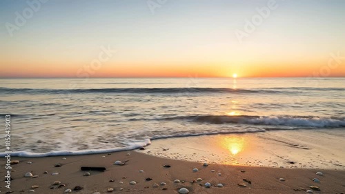 Golden Sunrise Over Gentle Ocean Waves with ShellStrewn Beach Background.