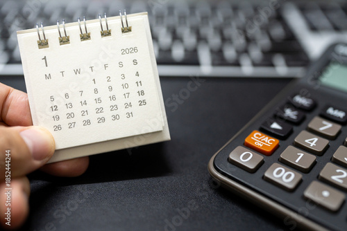 Hand holding January 2026 calendar with calculator for financial stress and budget crisis concept. financial anxiety, calculating monthly expenses, debt management.