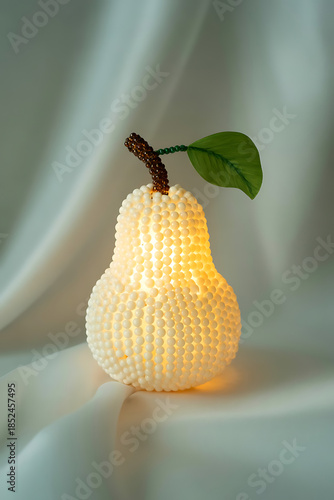 A decorative pearshaped lamp emitting a soft warm glow, placed on a draped white fabric surface