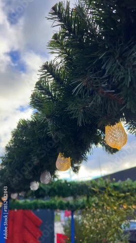 Bright lights hang from greenery in a bustling outdoor area. Christmas market in Gdansk, Poland