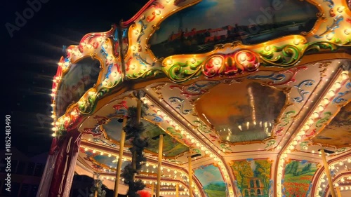 A carousel with bright lights and decorations turns in a city park as people enjoy the festive atmosphere during Christmas market scene