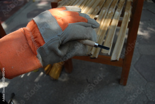 Artisanal process of covering door windows with natural bamboo sticks using basic hand tools and safety gloves