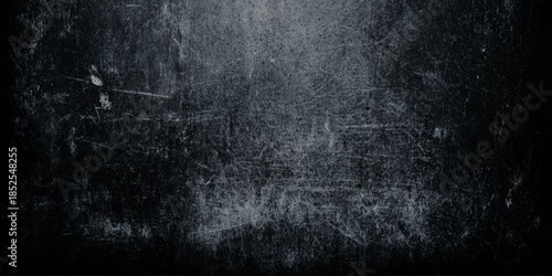 A dark and grainy texture dominates the image featuring scratches and imperfections across a black surface