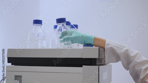 Close up lab worker change mobile phase of HPLC system.