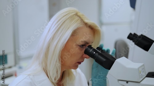 Close up researcher using optical microscope for sample study.