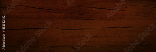 Dark brown wooden texture with grain pattern on floor planks or table background. Timber surface of rustic material for vintage interiors, natural board design and warm atmospheric backdrops.