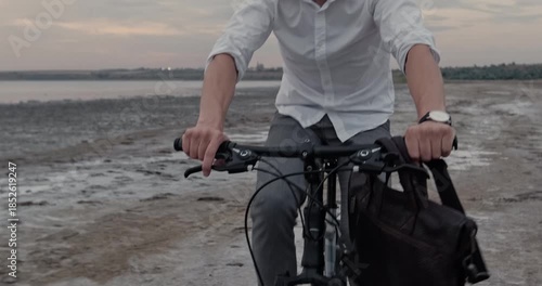 Straining man pedals forcefully across wet sand beach fighting resistant terrain showing thumbs-up. Bearded man maintains intense rhythm navigating difficult shoreline