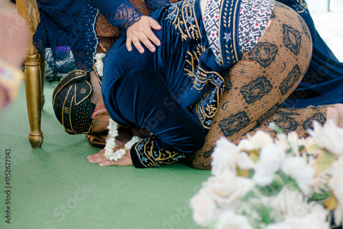 Tableau sur toile Close-up of a groom performing the traditional Javanese Sungkeman ritual to seek parents' blessing