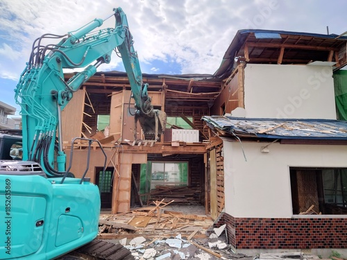 Foto Demolition of a residential wooden house with a blue excavator showing interior