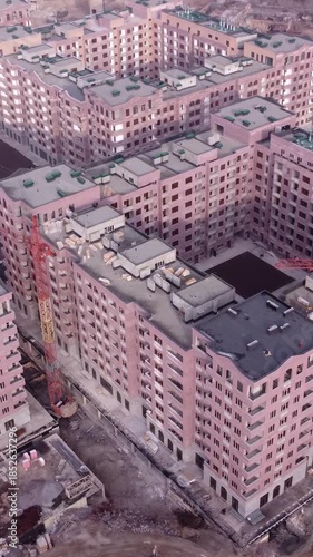Aerial view of an unfinished apartment block with active cranes at the construction site