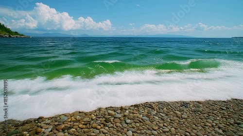 Serene ocean waves crash on rocky shoreline with lush greenery