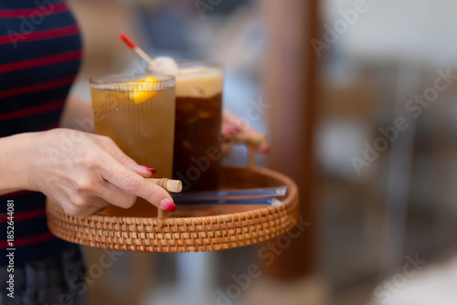 Fotografie Woman is carrying a tray with drinks back to a table inside the cafe