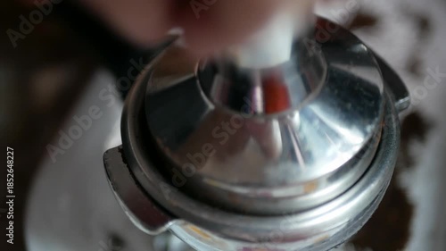 close up to hand using coffee tamper stamp into coffee Portafilter bucket full with grounded coffee bean to make espresso for morning hot beverage drink, coffee brew morning drink