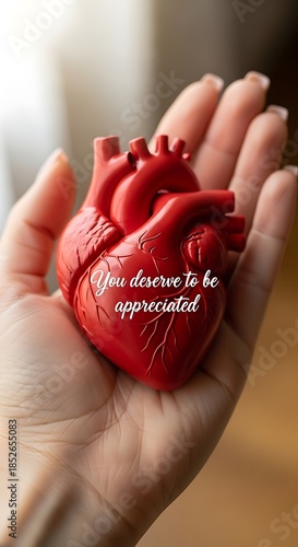 Hand holding a red heart model with appreciation message