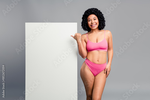 Young beauty model in pink bikini poses beside a white board for advertising and shopping campaigns highlighting confidence body positivity fitness fashion and lifestyle
