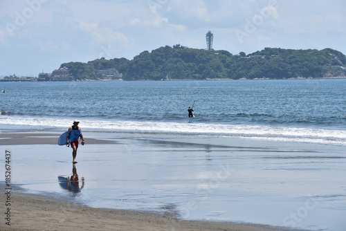 潮が引いた片瀬西浜海岸で海に入るサーファー