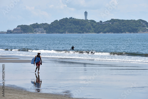 潮が引いた片瀬西浜海岸で海に入るサーファー