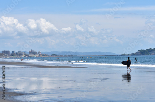 潮が引いた片瀬西浜海岸で海に入るサーファー