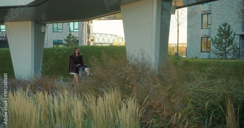 Mother pushing stroller with baby in modern residential park