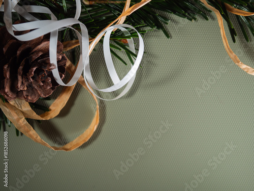 Christmas wrapping ribbonstring and pine cone on green background