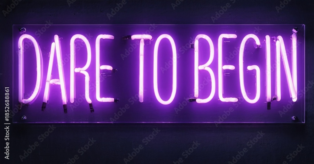 Bright purple neon sign displays words Dare To Begin against dark wall. Minimalist design, inspirational message, modern aesthetic.