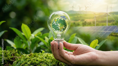 Hand holding light bulb with green planet earth inside. Eco energy concept