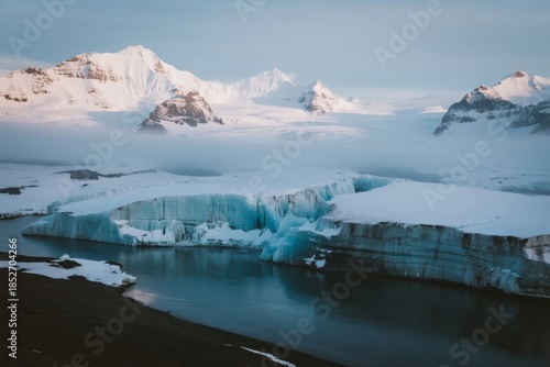 Glacial landscape with ice formations and snow-capped mountains reflecting in calm water