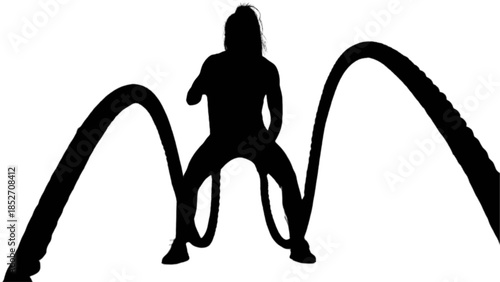 Athletic woman exercising with battle ropes in a dark gym.