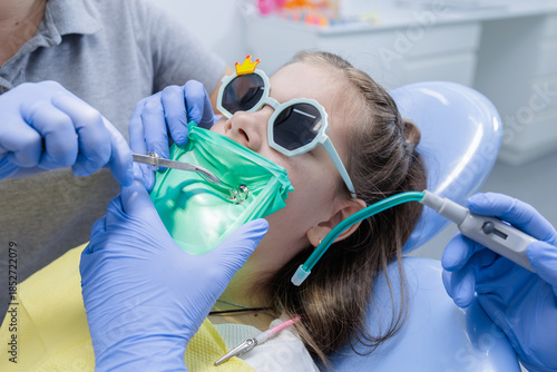Fotografie Fear free pediatric dental procedure with rubber dam isolation and protective ey
