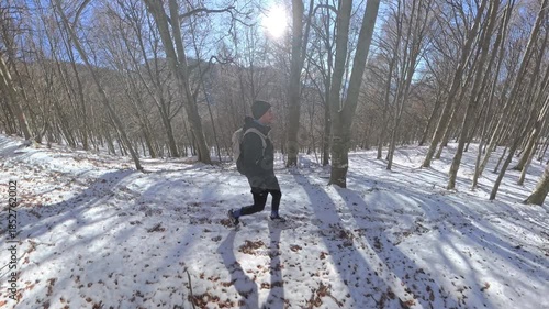 Monte Lema, Varese, Italy: A hiker man black dressed walks in the winter wood on the snow