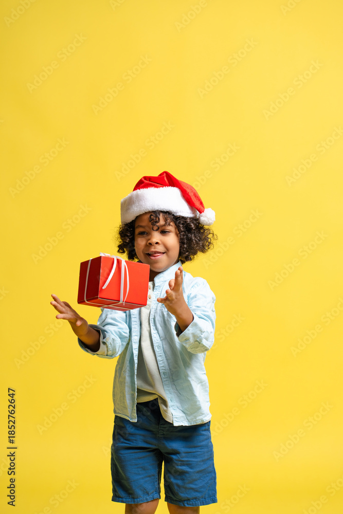 Obraz premium Happy child celebrating the holiday season, catching his red present
